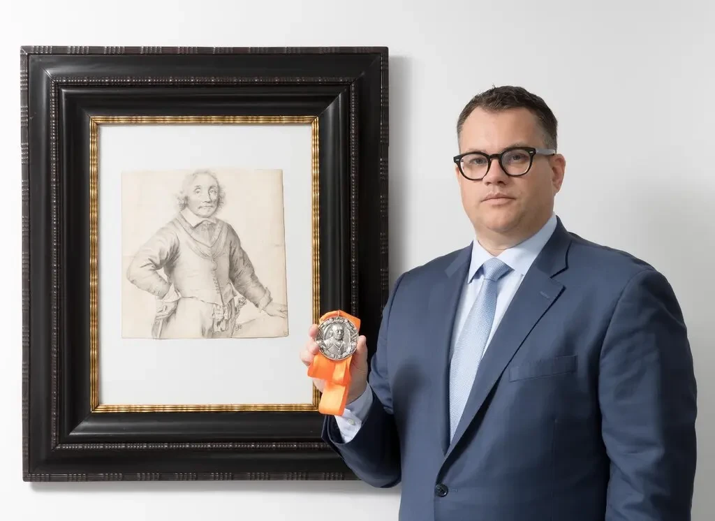 Christopher Bishop mit dem <em>Portrait of Admiral Maarten Harpertszoon Tromp (1597–1653)</em> by Jan Lievens, ca. 1652/53 and a 17th century silver commemorative medal depicting the admiral.  Photo courtesy of Christopher Bishop Fine Art, New York.  ” width=”1024″ height=”746″ srcset=”/app/news-upload/2022/06/16sp-tefaf-drawing-inyt2-jumbo.webp 1024w, https:/ /news.artnet.com/app/news-upload/2022/06/16sp-tefaf-drawing-inyt2-jumbo-300×219.webp 300w, https://news.artnet.com/app/news-upload/2022/ 06/16sp-tefaf-drawing-inyt2-jumbo-50×36.webp 50w” sizes=”(max-width: 1024px) 100vw, 1024px”/></p>
<p id=